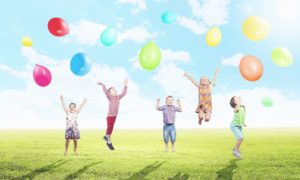 青空の下カラフルな風船と遊ぶ子供たち